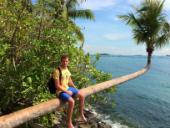 Photo of study abroad student Dylan sitting on a palm tree